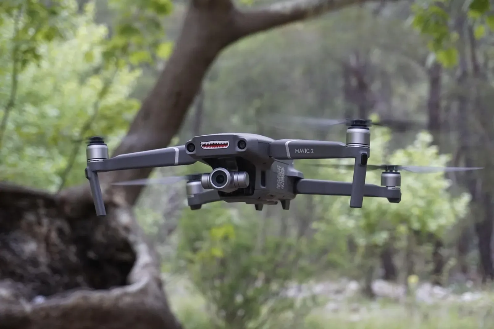 Close-up of a foldable Dronemie drone resting on a rock beside a backpack during an outdoor adventure
